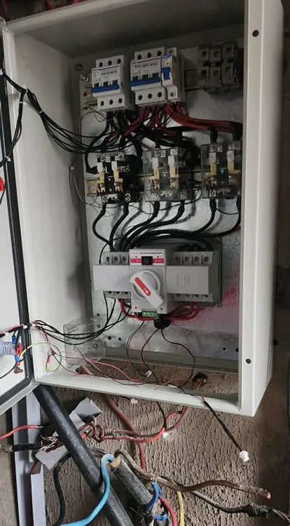 Automatic change over switch. It is filled with various electrical components, including circuit breakers at the top, contactors, and a large central rotary disconnect switch. 